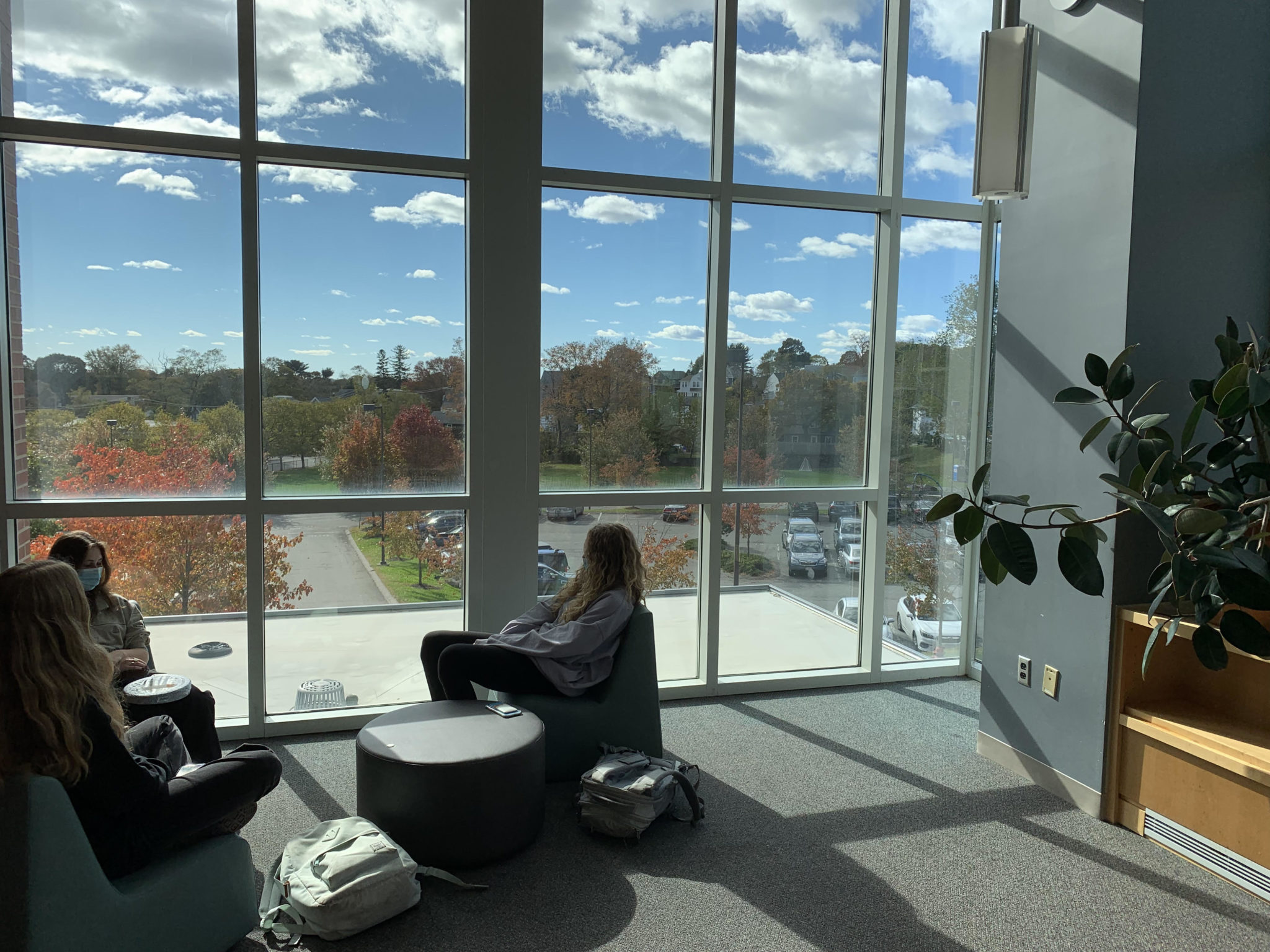 Students in library in front of windows in cozy seating